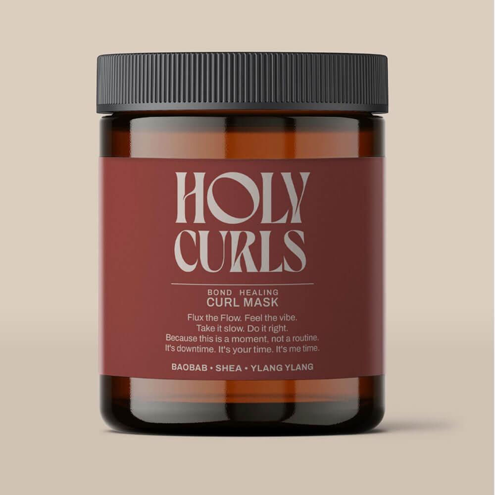 Jar of 'Holy Curls' curl mask with a maroon label on a beige background