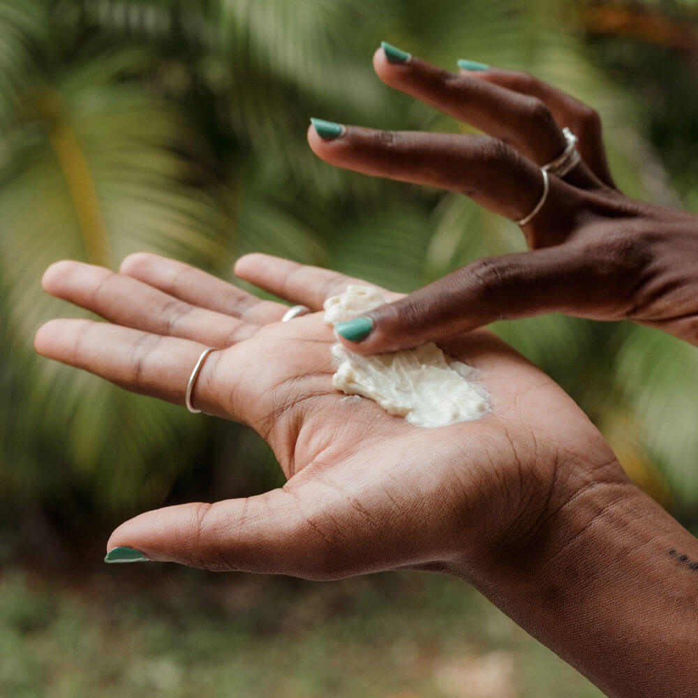 Two hands holding a small amount of white powder against a blurred green background