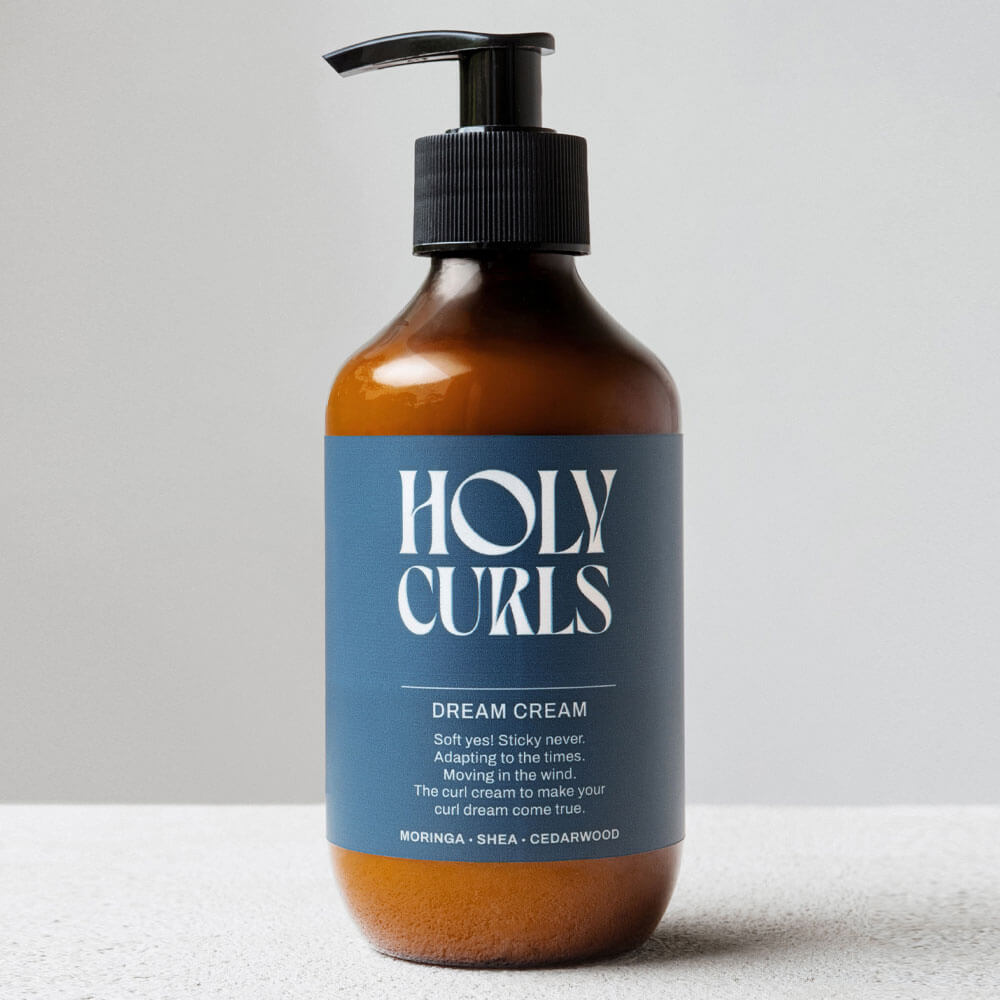 Bottle of Holy Curls Dream Cream with a pump on a light gray background