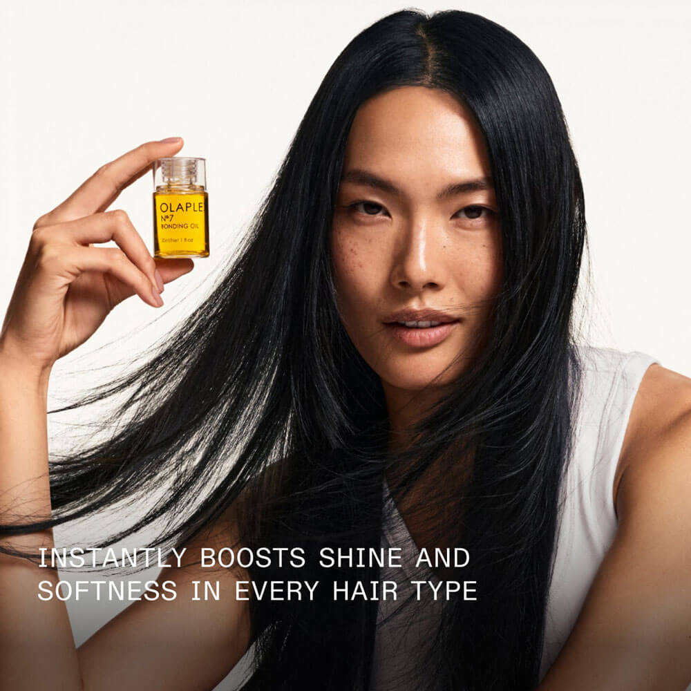 Woman holding a bottle of hair oil with text about its benefits
