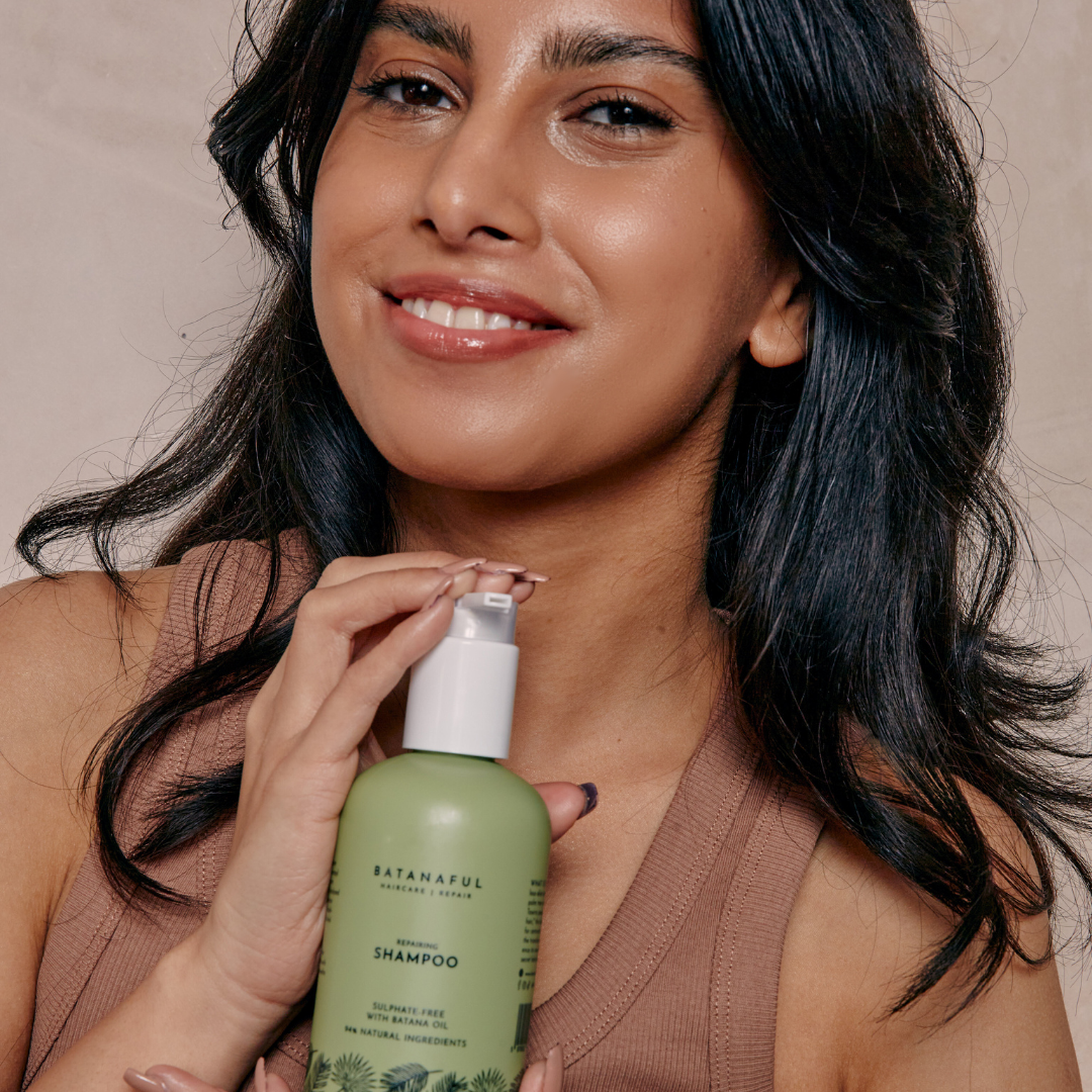 Woman holding a green shampoo bottle with a neutral background