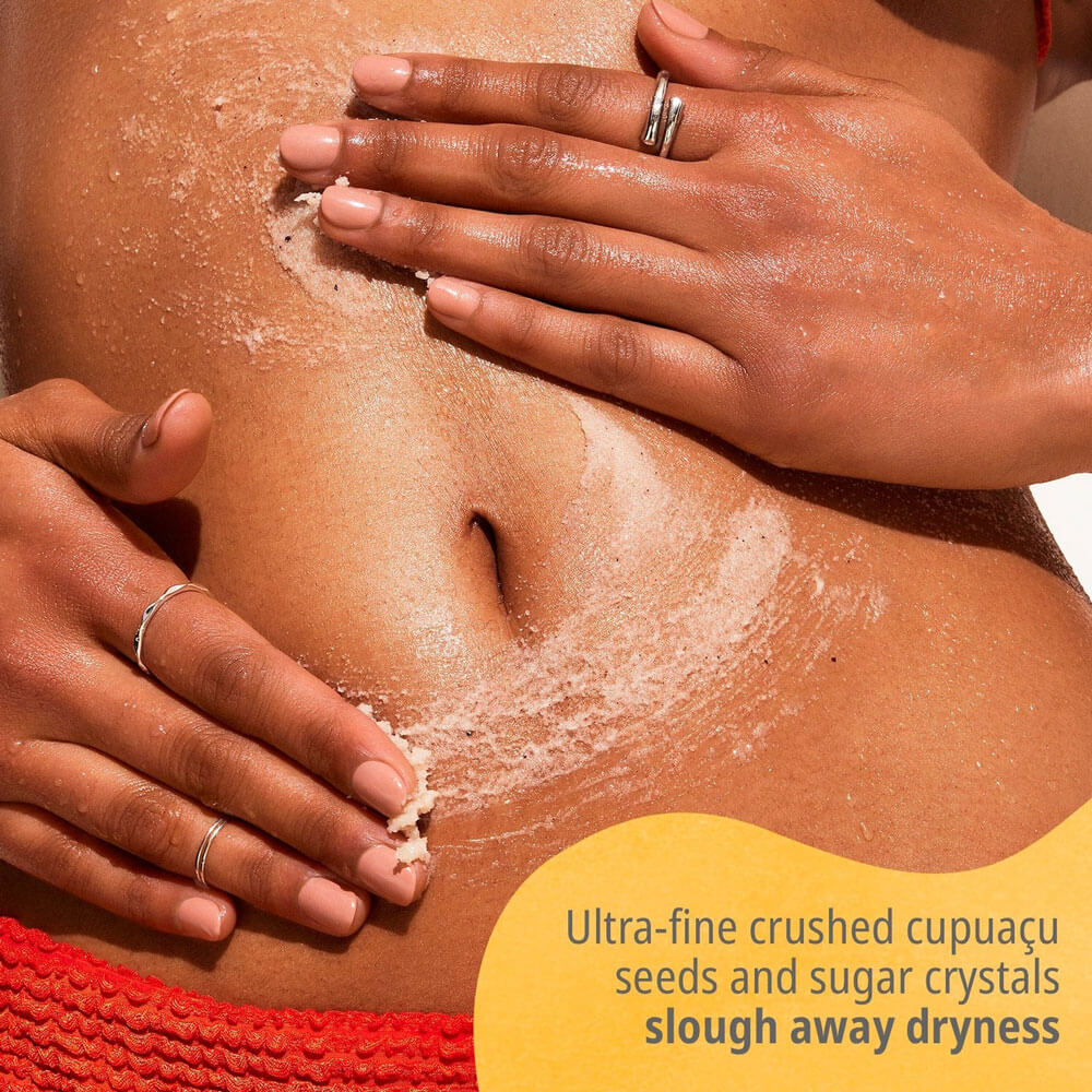 Person applying a scrub to their skin with a yellow label indicating product benefits.