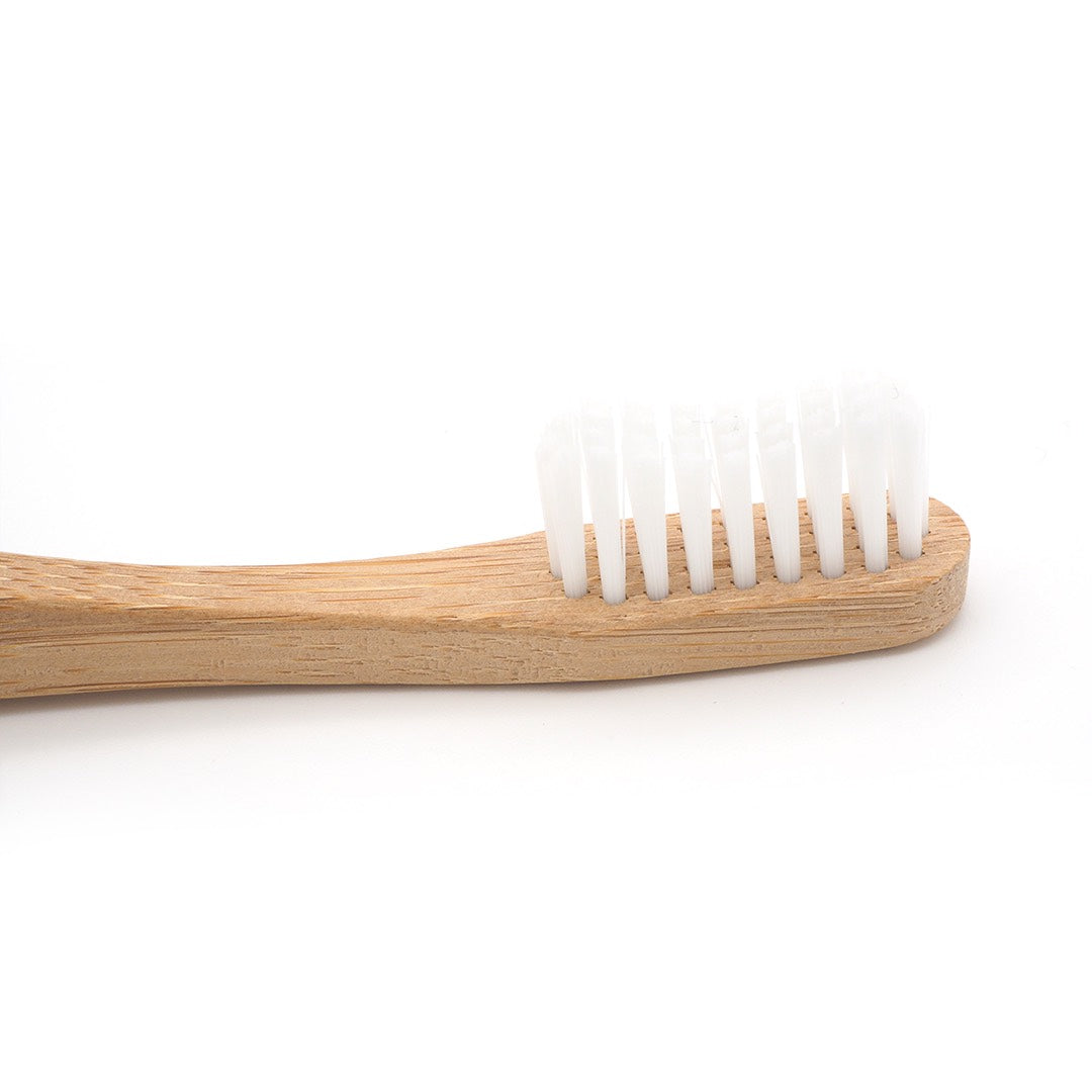 Bamboo toothbrush with white bristles on a white background