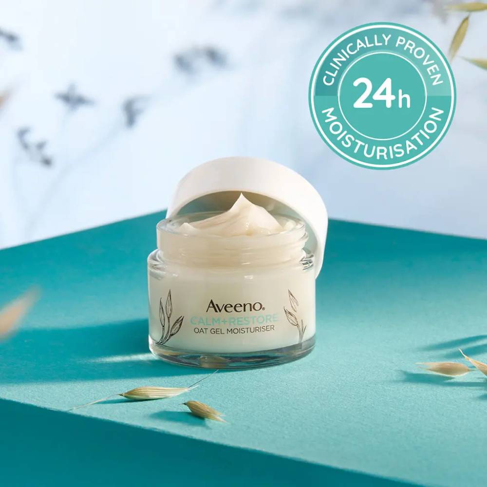 Aveeno oat gel moisturizer jar on a blue surface with a blurred natural background