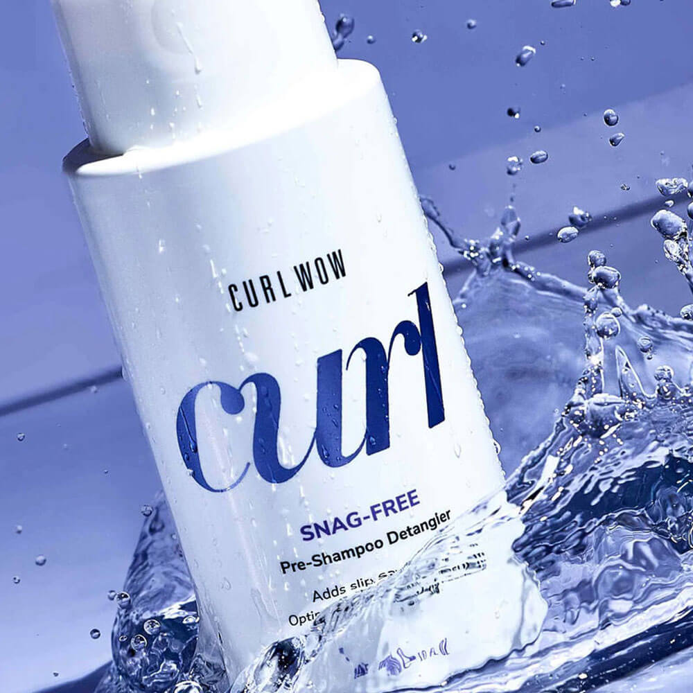 Curl Wow Snag-Free Pre-Shampoo Detangler bottle with water droplets and splashes on a blue background