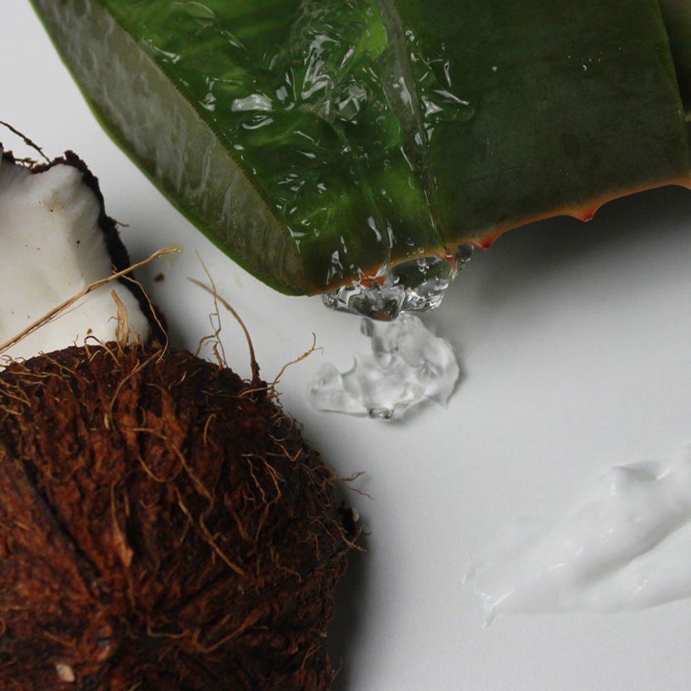 Close-up of aloe vera leaf with gel dripping onto a white surface.