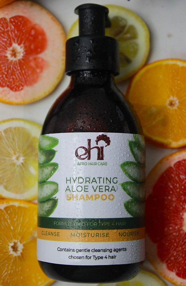 Shampoo bottle with aloe vera label on a background of sliced citrus fruits