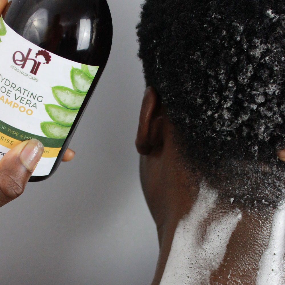 Person using a bottle of ehi shampoo on their hair with a gray background