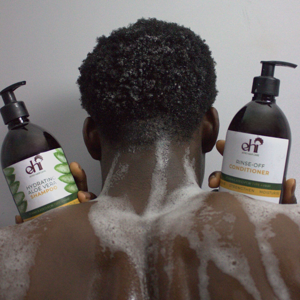 Person with shampoo and conditioner bottles, showing hair care routine.