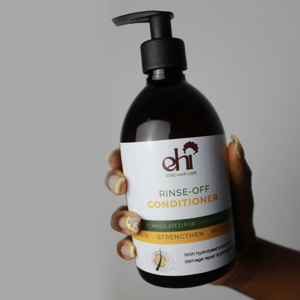 Hand holding a bottle of 'ehi' rinse-off conditioner against a neutral background