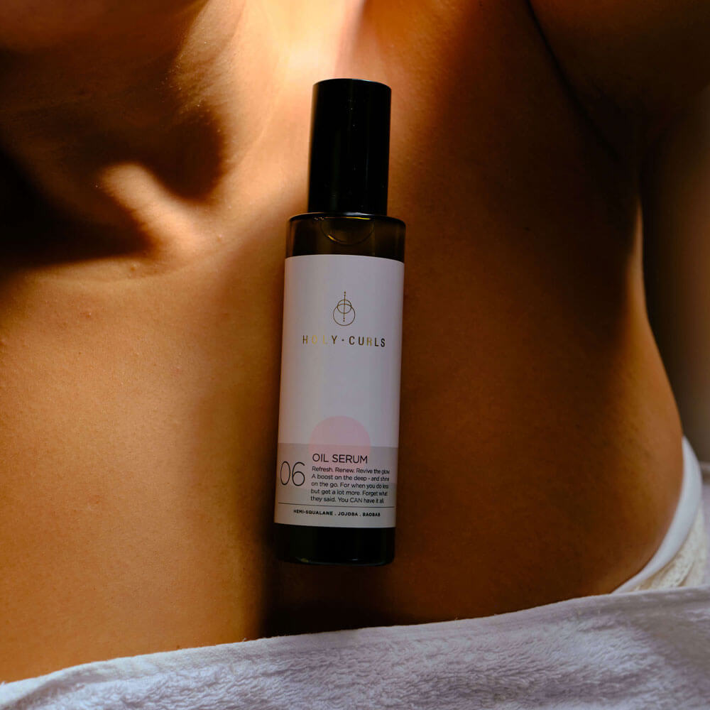 Oil serum bottle labeled '06' on a person's shoulder with a blurred background