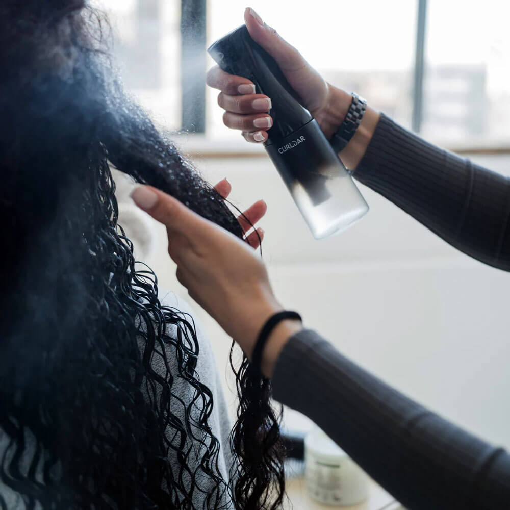 Person using a hair dryer on another person's hair in a salon setting.