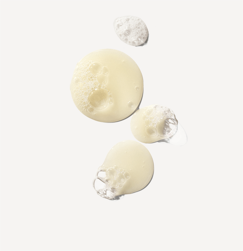 Three droplets of a white cream-like substance on a light gray background