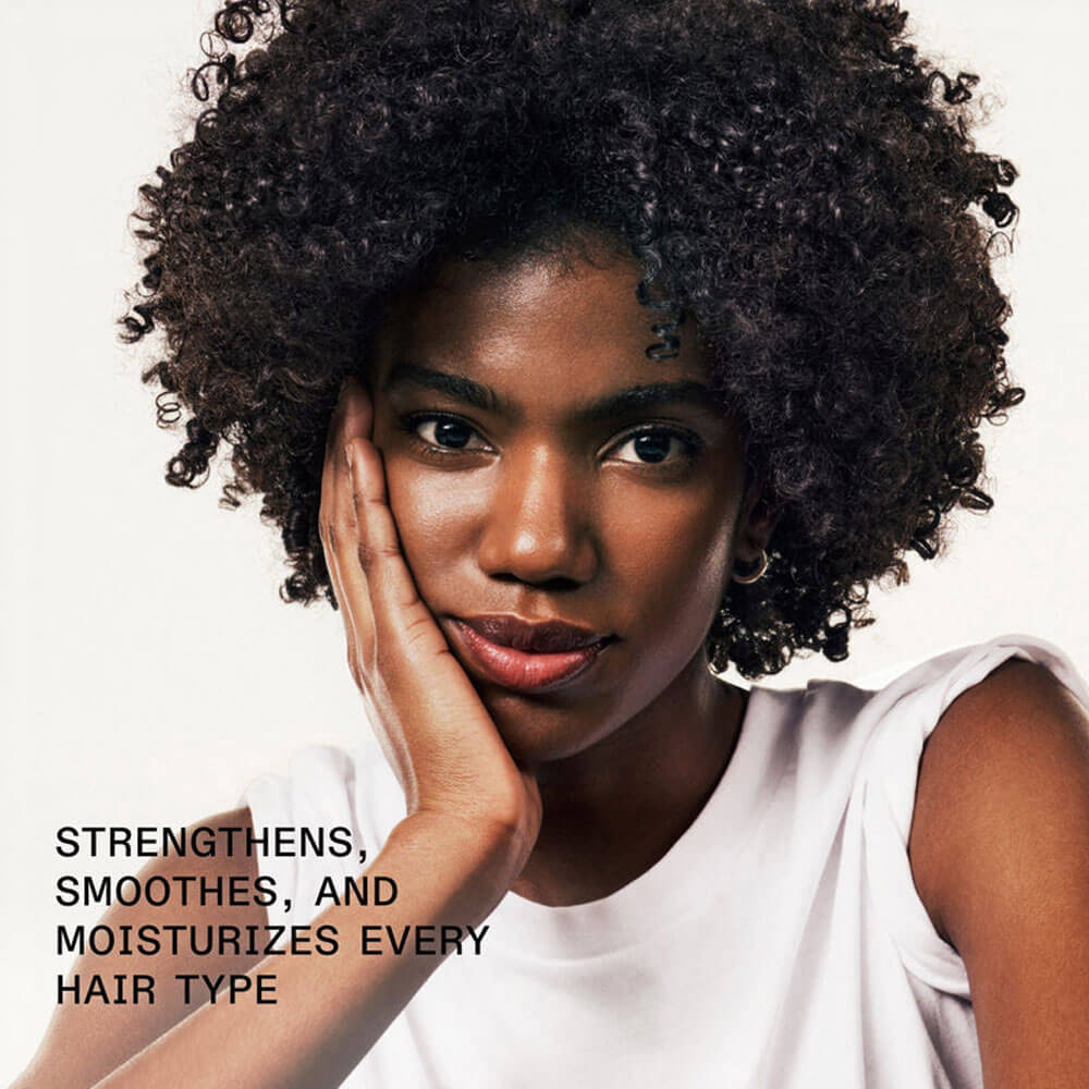 Woman with curly hair wearing a white top against a white background