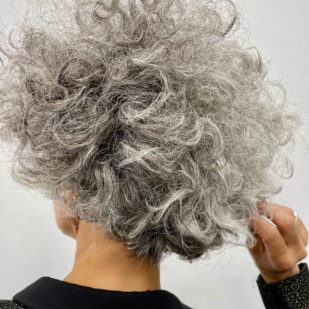 Close-up of a person with gray, curly hair against a light background