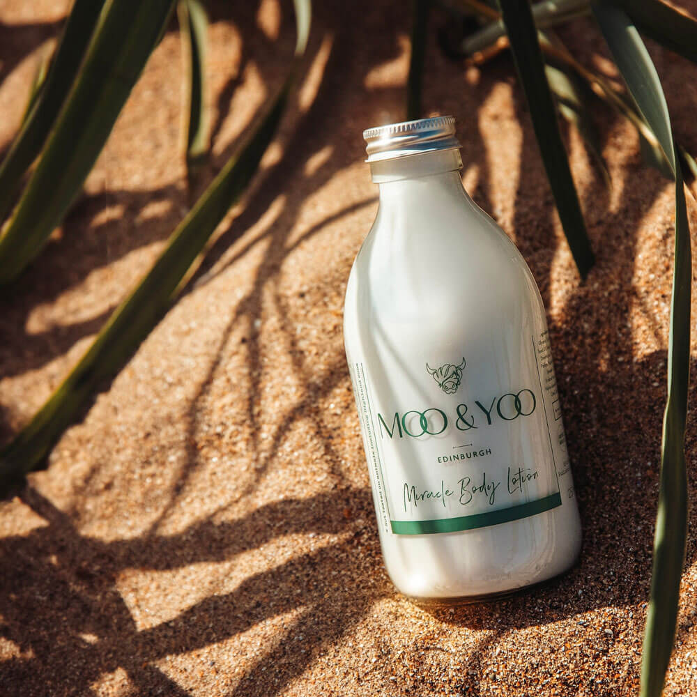 Moo & Yoo bottle of lotion on a textured surface with plant shadows