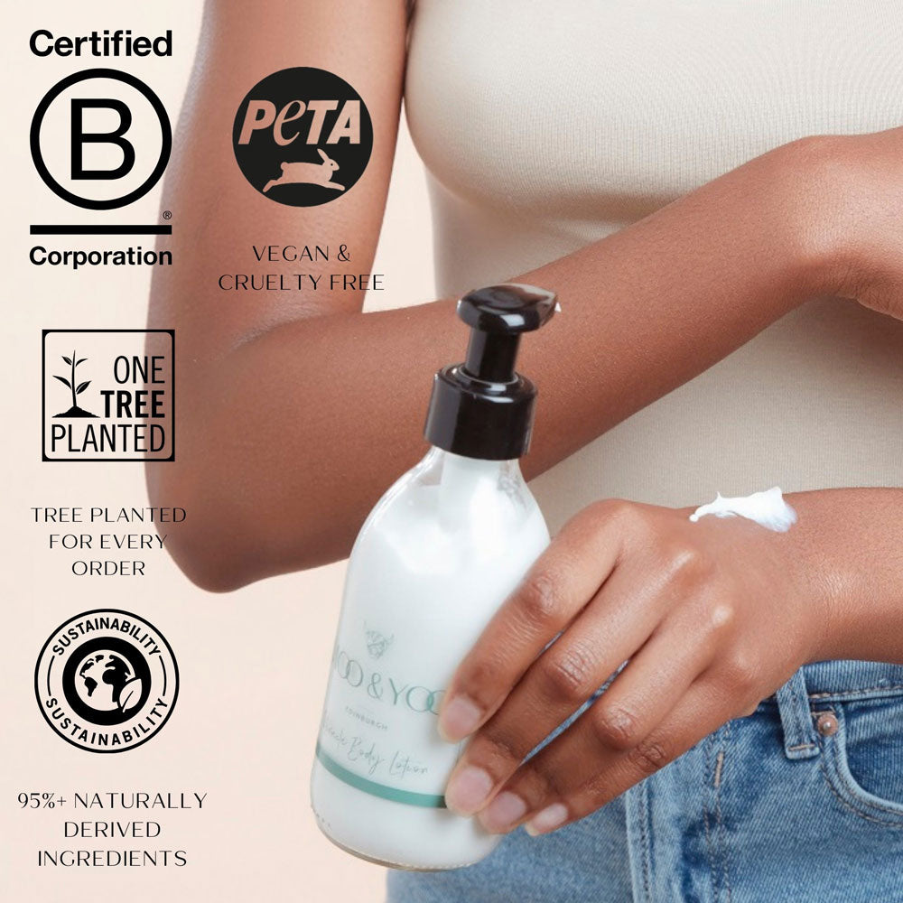 Person holding a bottle of body lotion with sustainability certifications displayed.