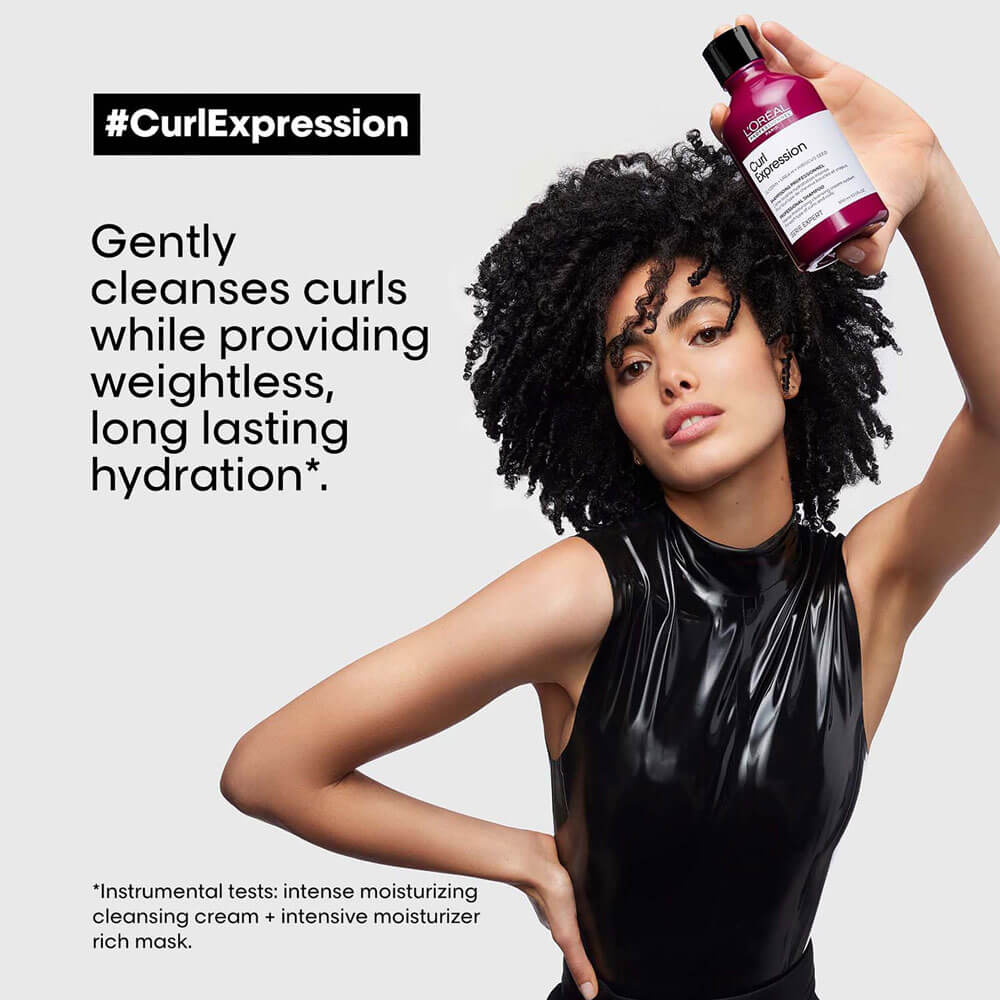 Woman holding a bottle of 'Curly Expression' product with text about hair care on a light gray background