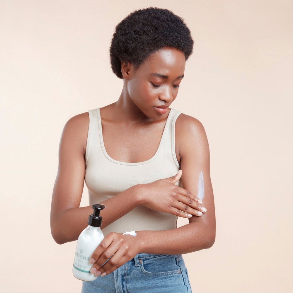 Woman applying lotion to her arm with a beige background